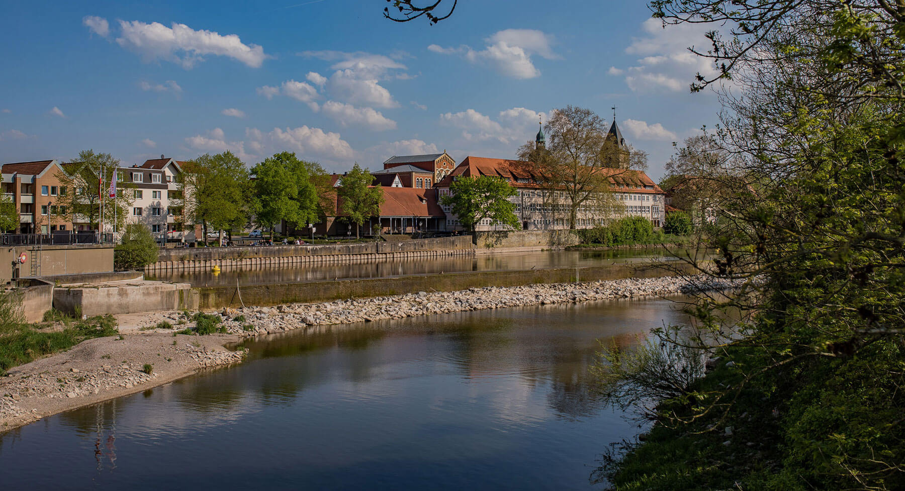 Ansicht auf die Weser mit dahinterliegenden Immobilien in Hameln